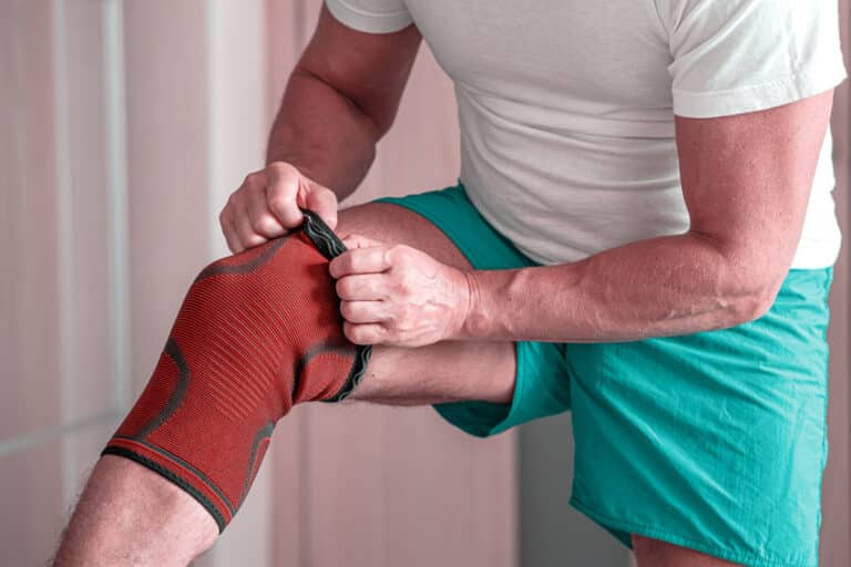 man adjusts a compression bandage on the knee joint. sports injury.